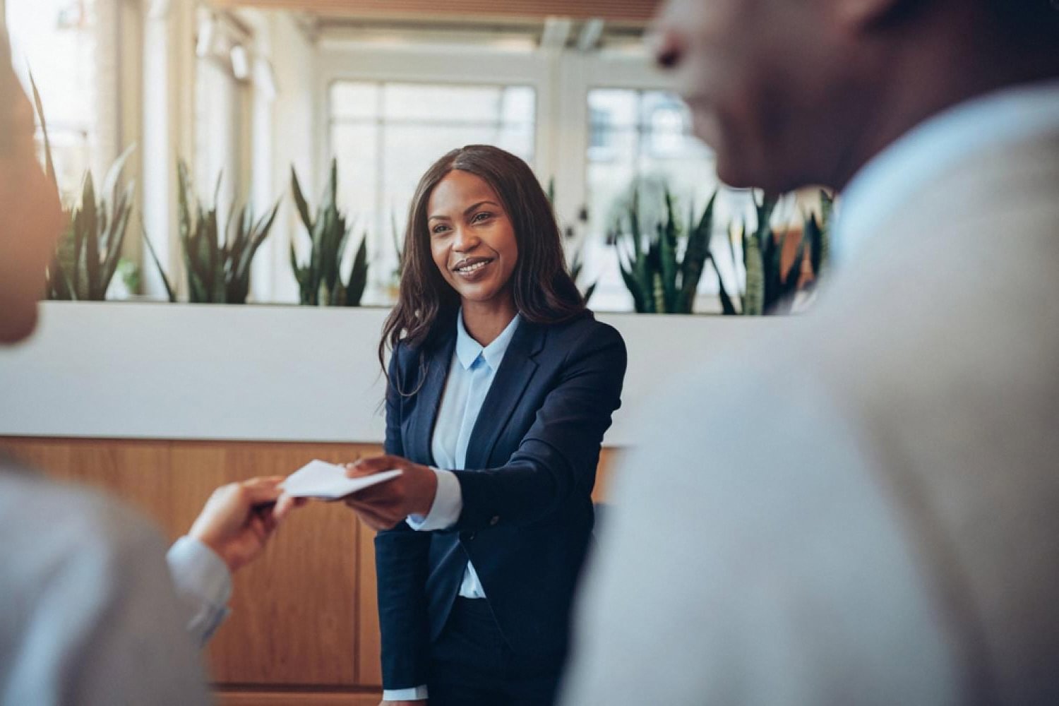 Smiling hotel receptionist handing a registration card to an arriving guest