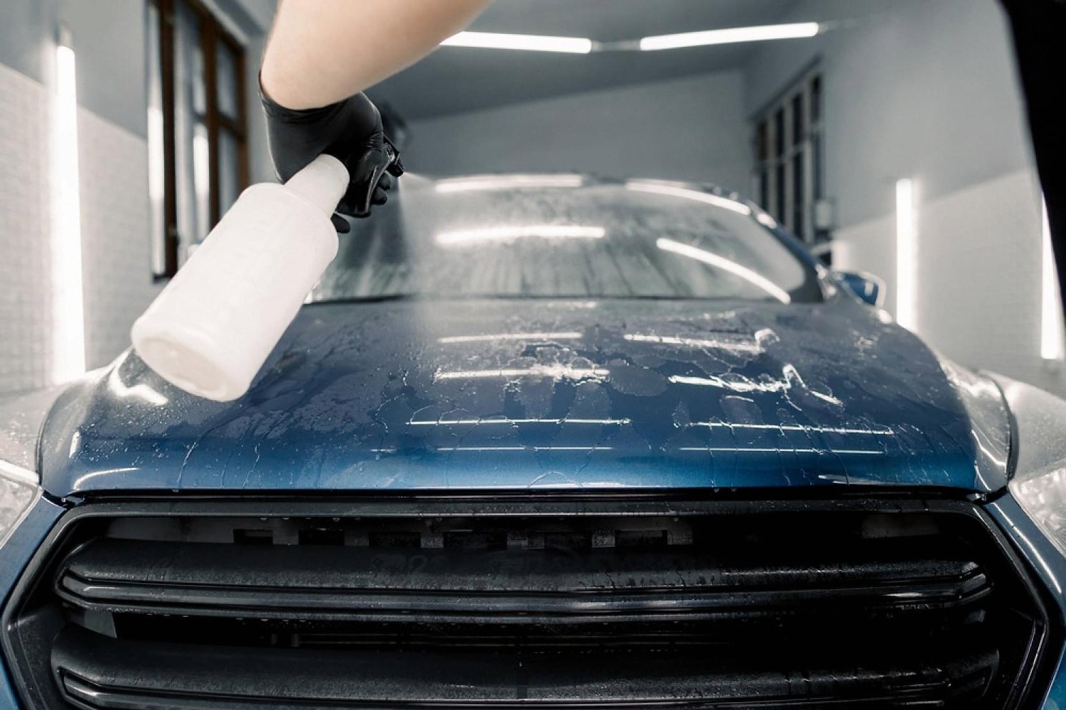 Gloved hand spraying slip solution during paint protection film installation