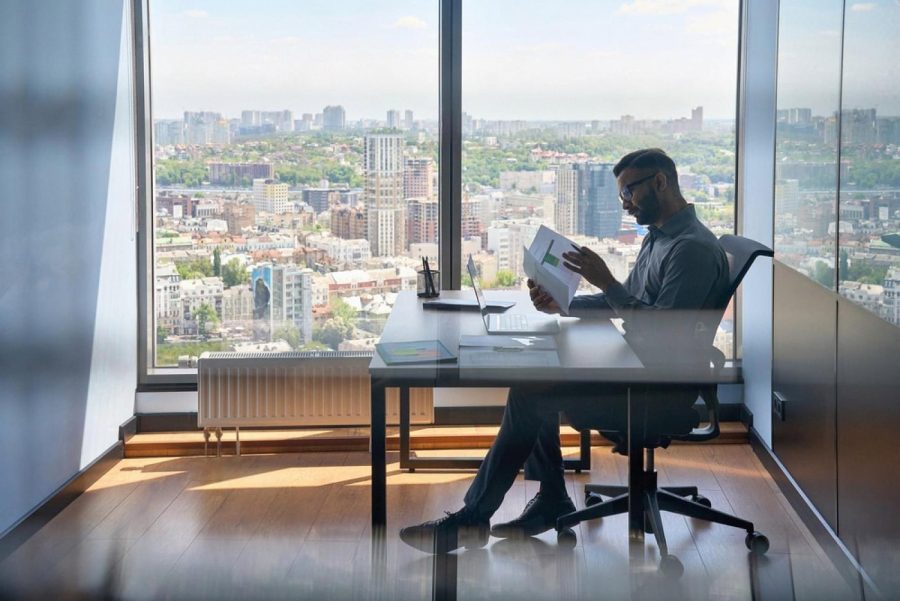 Businessman reviewing financial documents at a desk overlooking a UAE city skyline