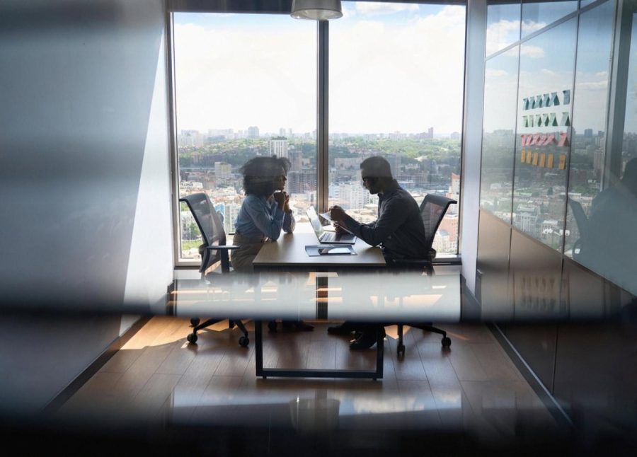 Two executives negotiating in a high-rise UAE boardroom during a due diligence meeting