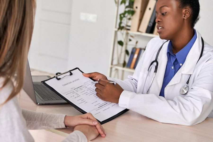 Doctor reviewing a medical insurance form with a client, illustrating group life insurance coverage for UAE employees