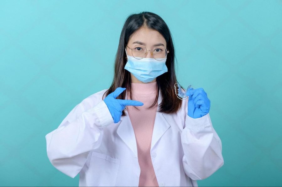 Orthodontist in Abu Dhabi holding a clear dental aligner and giving advice on braces care