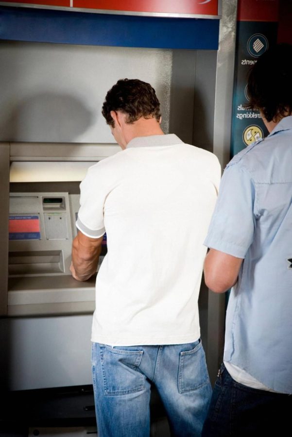 Two customers waiting in line at a bank ATM in the UAE